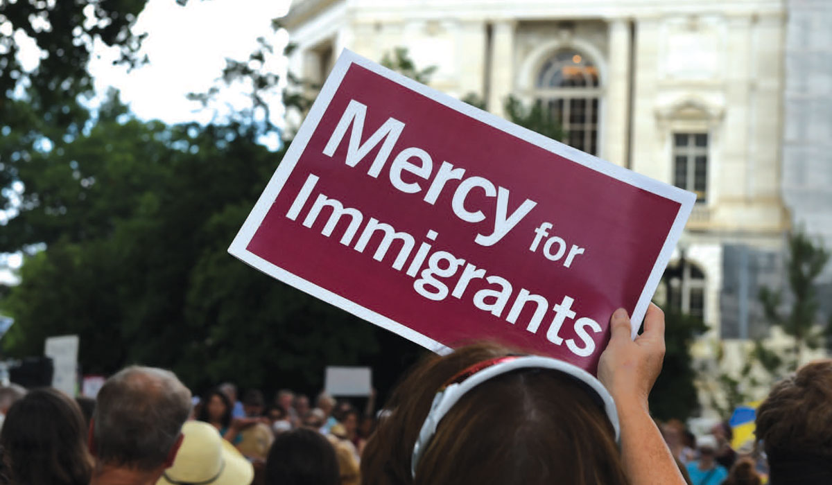Protestor holding sign that reads Mercy for Immigrants